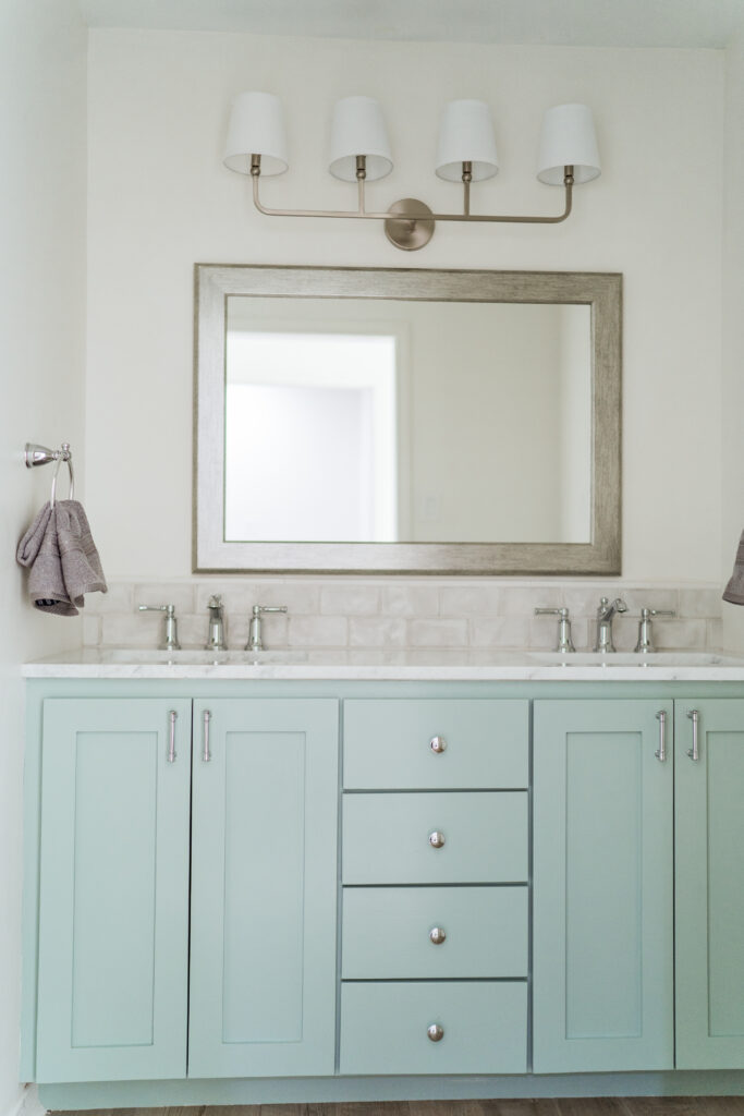 Spa-like bathroom makeover with custom overlay shaker style doors vanity painted in Sherwin Williams Quietude and classic 4-light sconce light fixture with shades | Adored by Alex